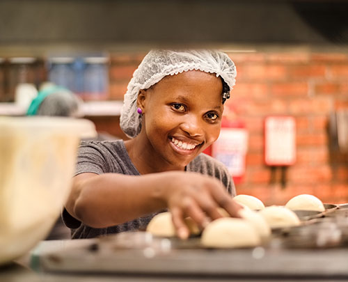 Smiling female student working at restaurant kitchen