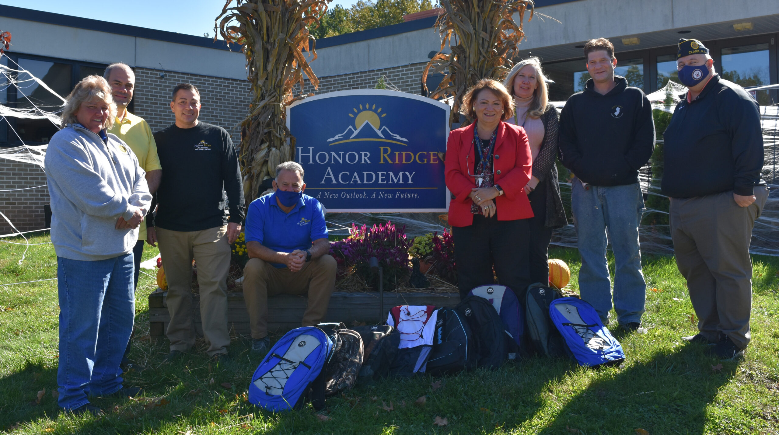 outdoor group photo of HRA staff and supporters involved in the backpack drive standing with the school sign